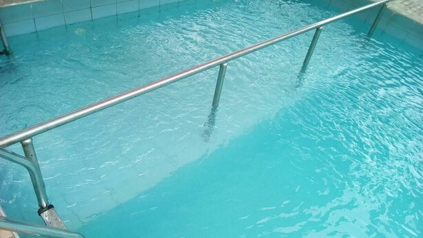 A swimming pool with a metal ladder and a tiled edge. - New Benny Rose   (Abuja)