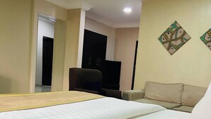 A hotel room with a bed, a sofa, a television, and a wall-mounted artwork. - New Benny Rose   (Abuja)