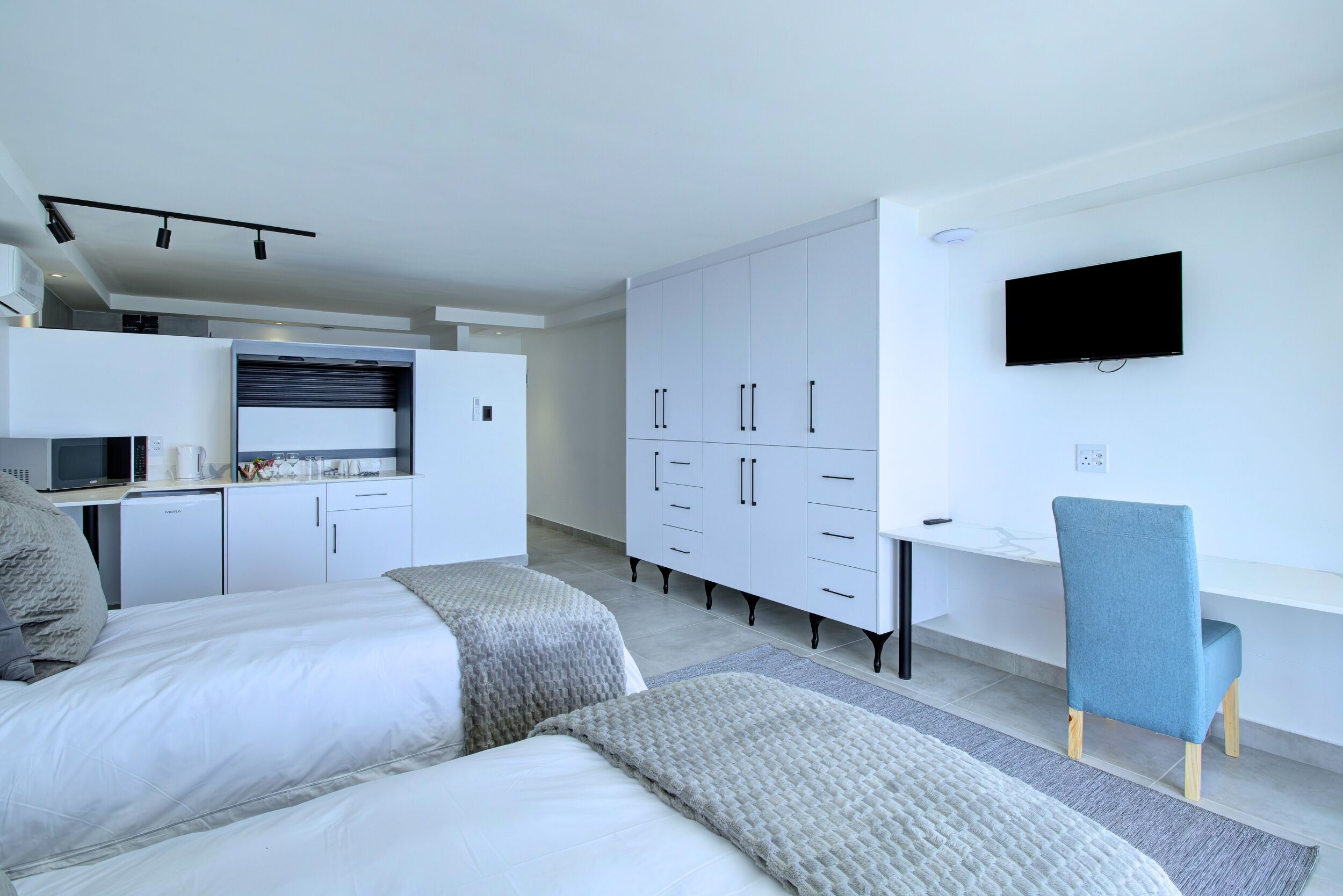Une chambre à coucher moderne, équipée d’un lit, d’un bureau et d’une télévision.