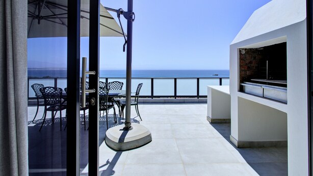 An outdoor patio with a table and chairs, a grill, and a view of the sea. - Mosselbay Waterfront Accomodation  (Mossel Bay)