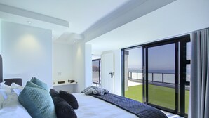 A modern hotel room with a large bed, a view of the sea through a sliding glass door, and a balcony with a view of the sea. - Mosselbay Waterfront Accomodation  (Mossel Bay)
