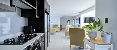 A modern kitchen with a stove, oven, and cabinets, leading to a living area with a sofa and a coffee table.