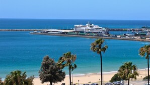 A cruise ship docked at a pier with a beach and palm trees in the foreground. - Mosselbay Waterfront Accomodation  (Mossel Bay)