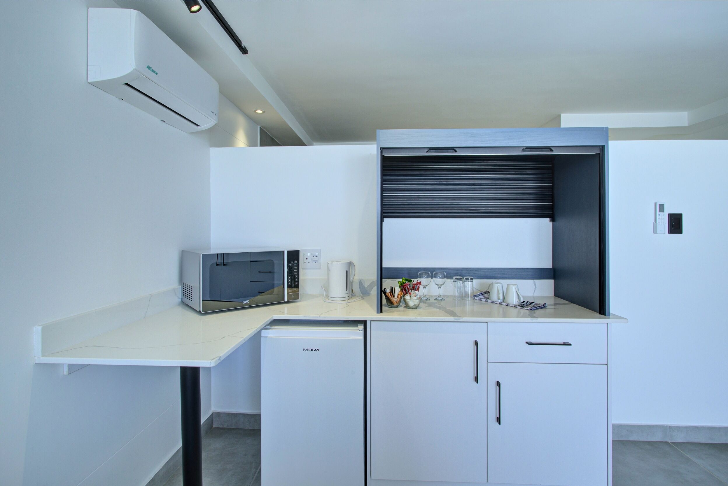 A compact kitchenette with a microwave, refrigerator, and a coffee maker on the countertop.