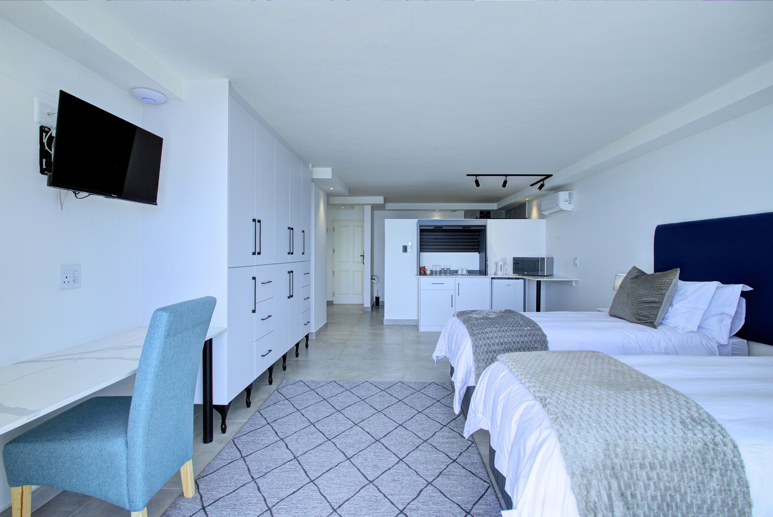 Una habitación de hotel moderna con cama, escritorio, silla y televisor.