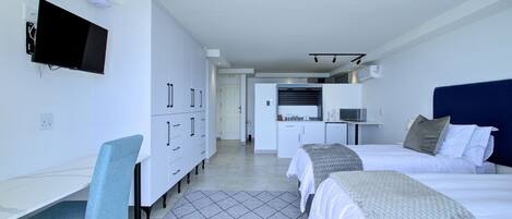 Una habitación de hotel moderna con cama, escritorio, silla y televisor.