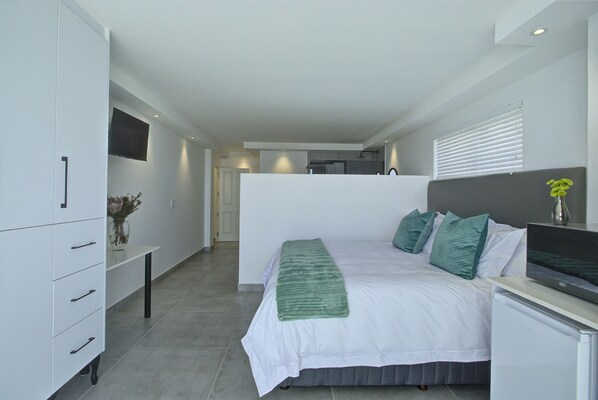 A modern bedroom with a bed, bedside table, and a TV. - Mosselbay Waterfront Accomodation (Mossel Bay)