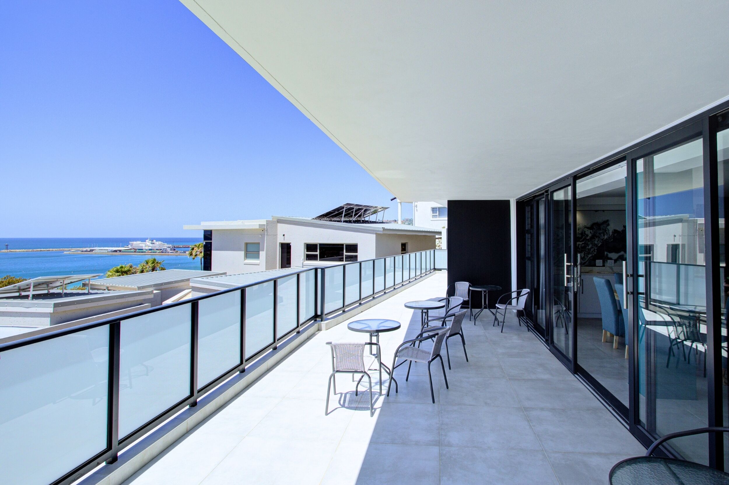 Un balcon doté d’une balustrade en verre, d’un espace salon extérieur et offrant une vue sur la mer.