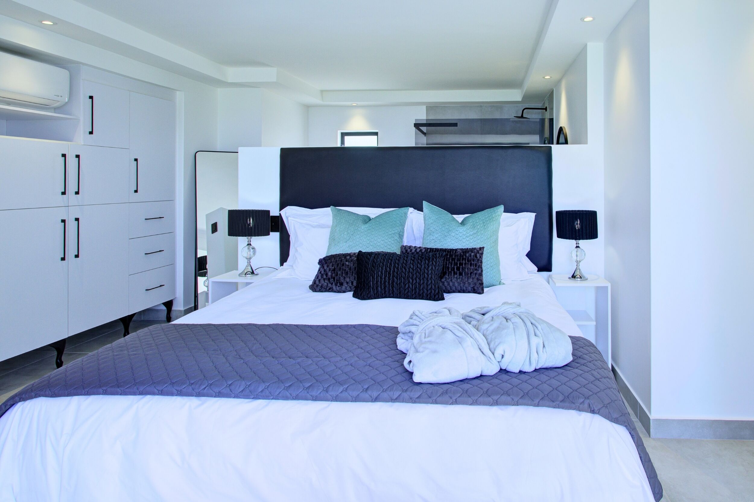 Een moderne hotelkamer met een groot bed, witte kasten en een zwart hoofdeinde.