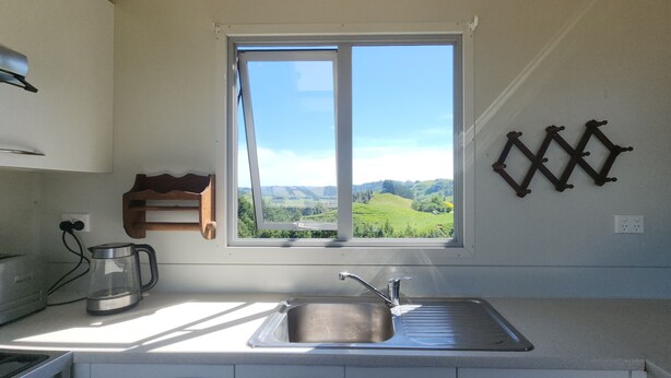 A kitchen with a window, a sink, a toaster, and a coffee maker.