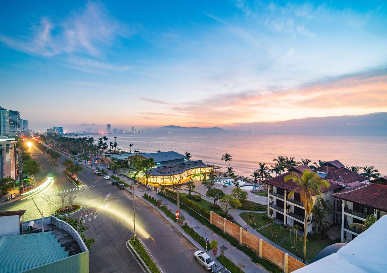A coastal hotel with a curved building, a swimming pool, and a view of the ocean.