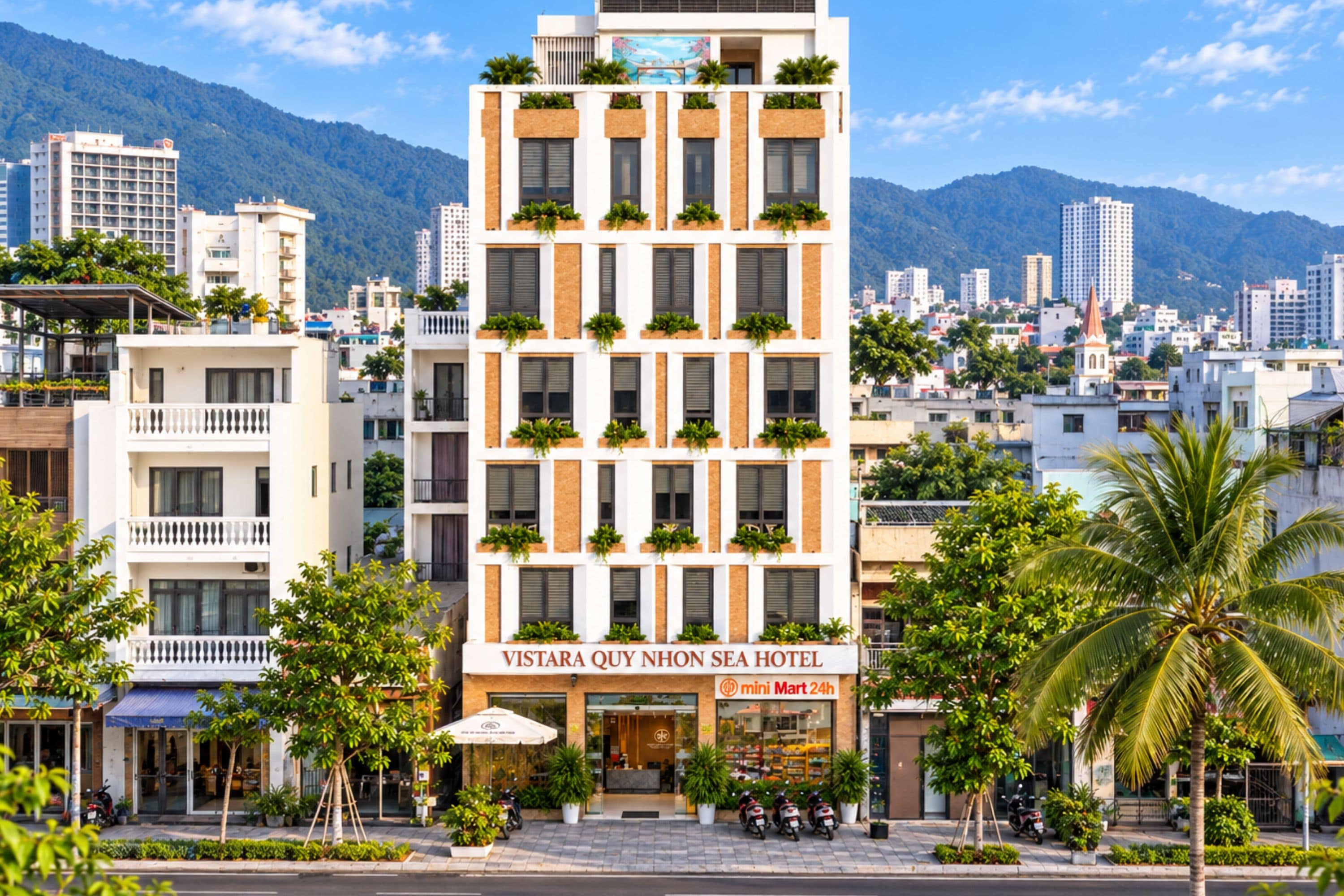 A multi-story hotel with a sign reading 'VISTARA QUY NHON SEA HOTEL' and a 'mini Mart 24h' sign.