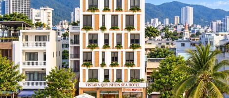A multi-story hotel with a sign reading 'VISTARA QUY NHON SEA HOTEL' and a 'mini Mart 24h' sign.