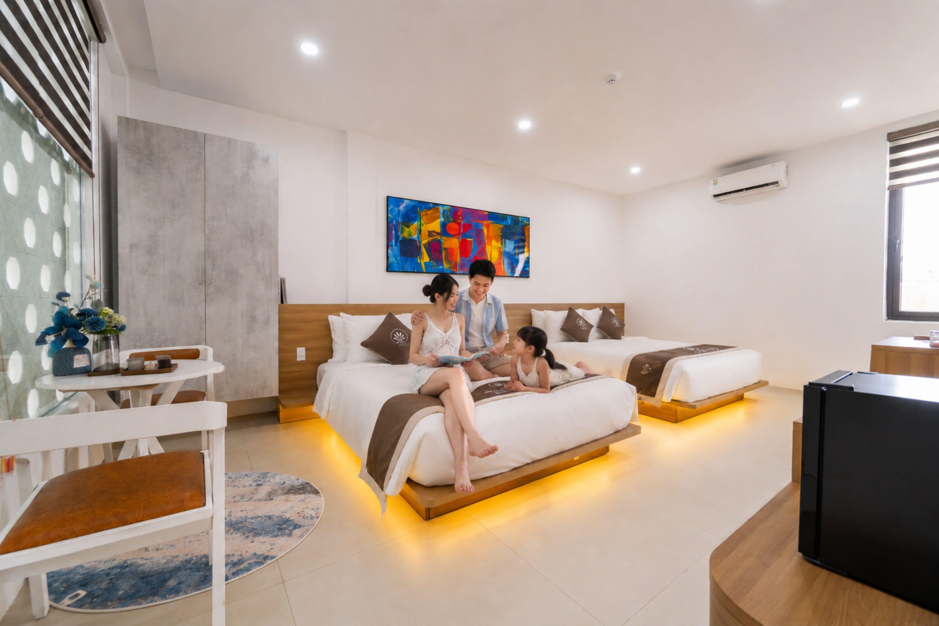 Quarto de hotel moderno com uma cama, mesas de cabeceira, uma TV e um quadro abstrato grande na parede.