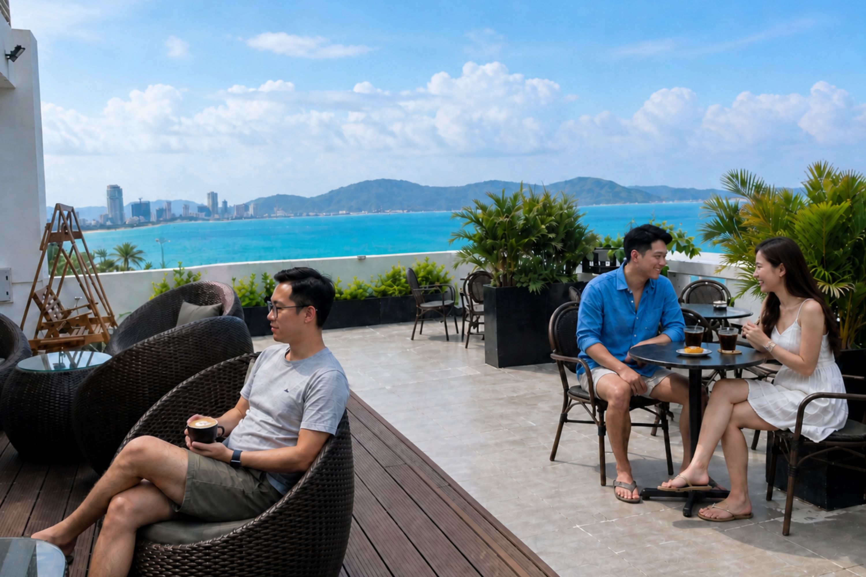 Una terraza con mobiliario de mimbre, una mesa con bebidas y vistas al mar y al horizonte de la ciudad.