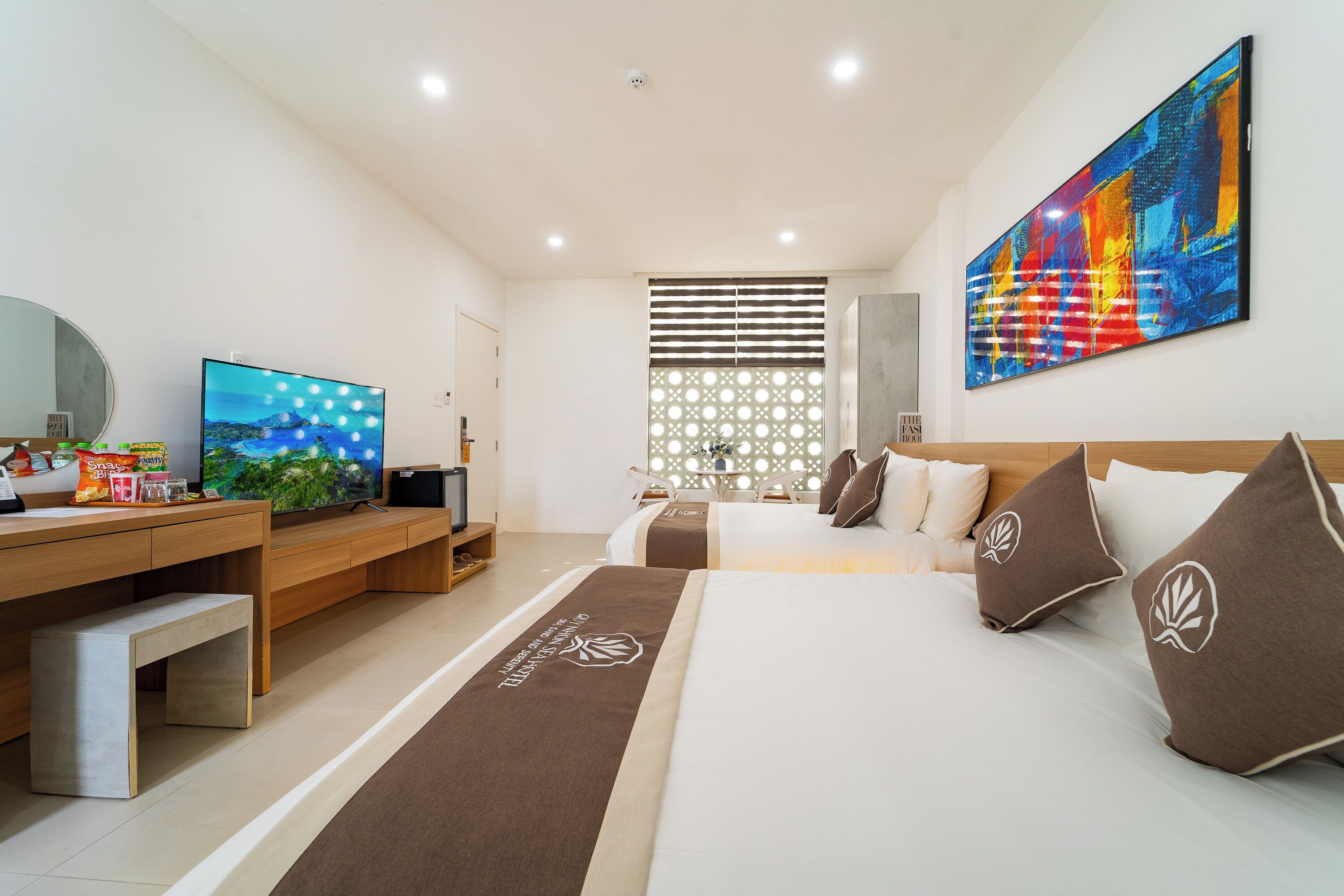 A modern hotel room with a large bed, a desk, and a television.