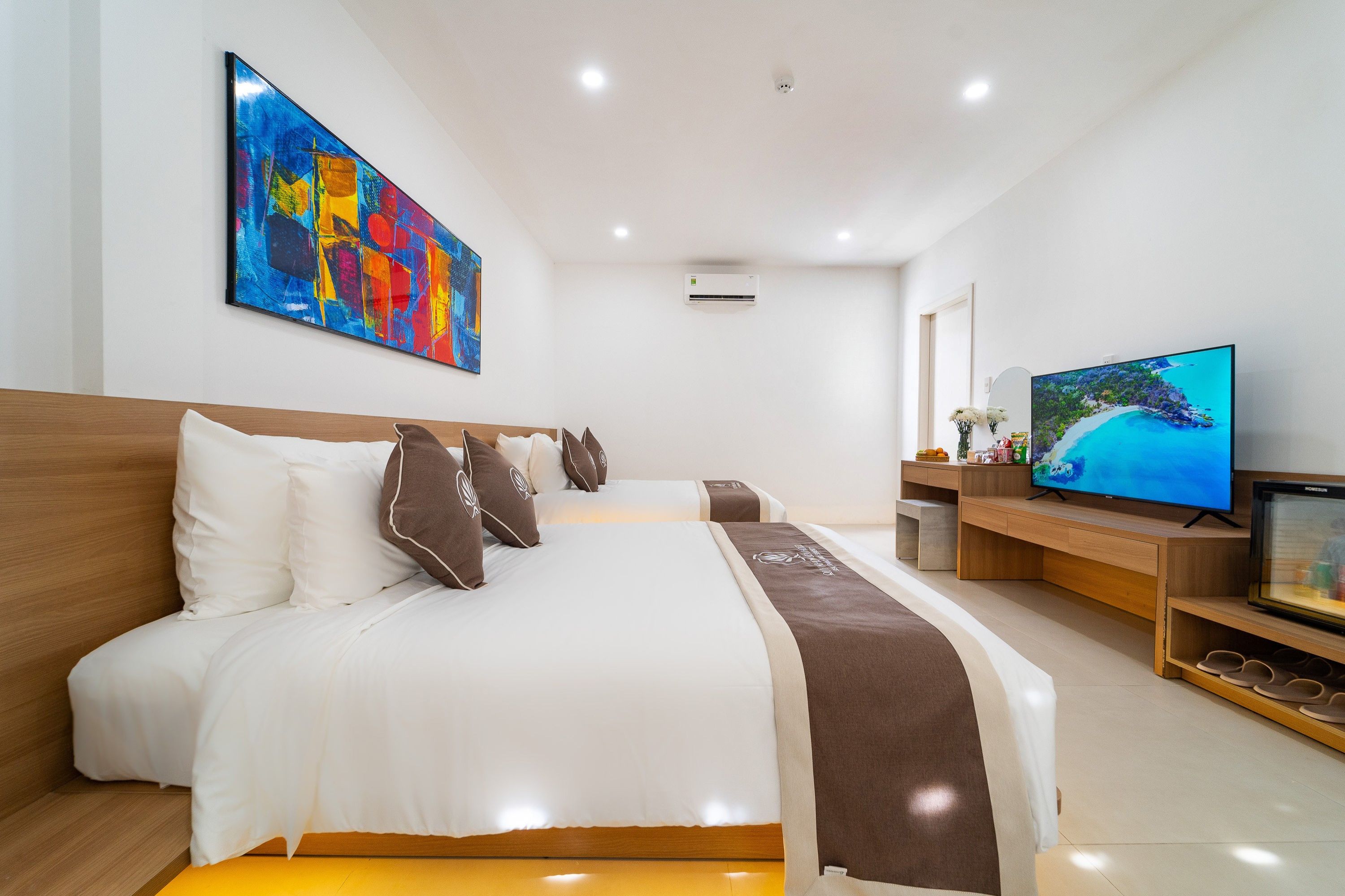 A hotel room with a large bed, a television, and a painting on the wall.