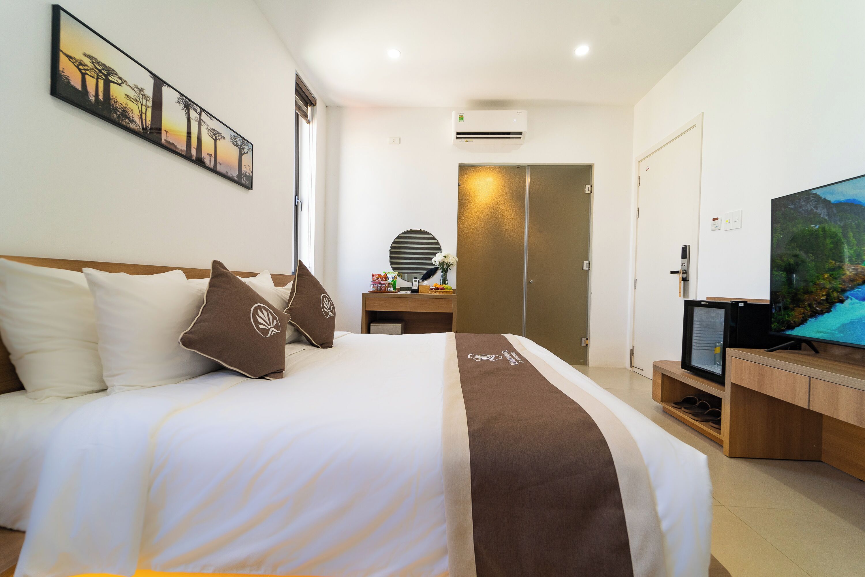 Una habitación de hotel con una cama grande, televisión, escritorio y armario.
