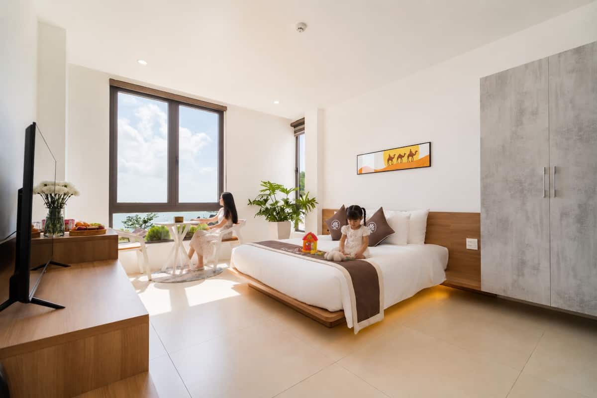 Un dormitorio moderno con una cama grande, un escritorio, un televisor y una ventana con vistas.