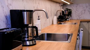 Une cuisine moderne équipée d’une machine à café, d’un évier et d’un lave-vaisselle.