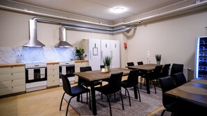Une cuisine moderne dotée d’appareils électroménagers intégrés, un coin repas avec une grande table et des chaises, et un petit réfrigérateur.
