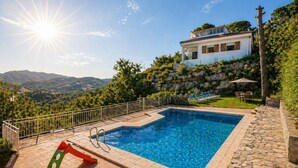 A rectangular swimming pool with a stone border, a metal railing, and a view of a house with a balcony. - Spectacular views, just 4km to the beach! (Sant Cebrià de Vallalta)