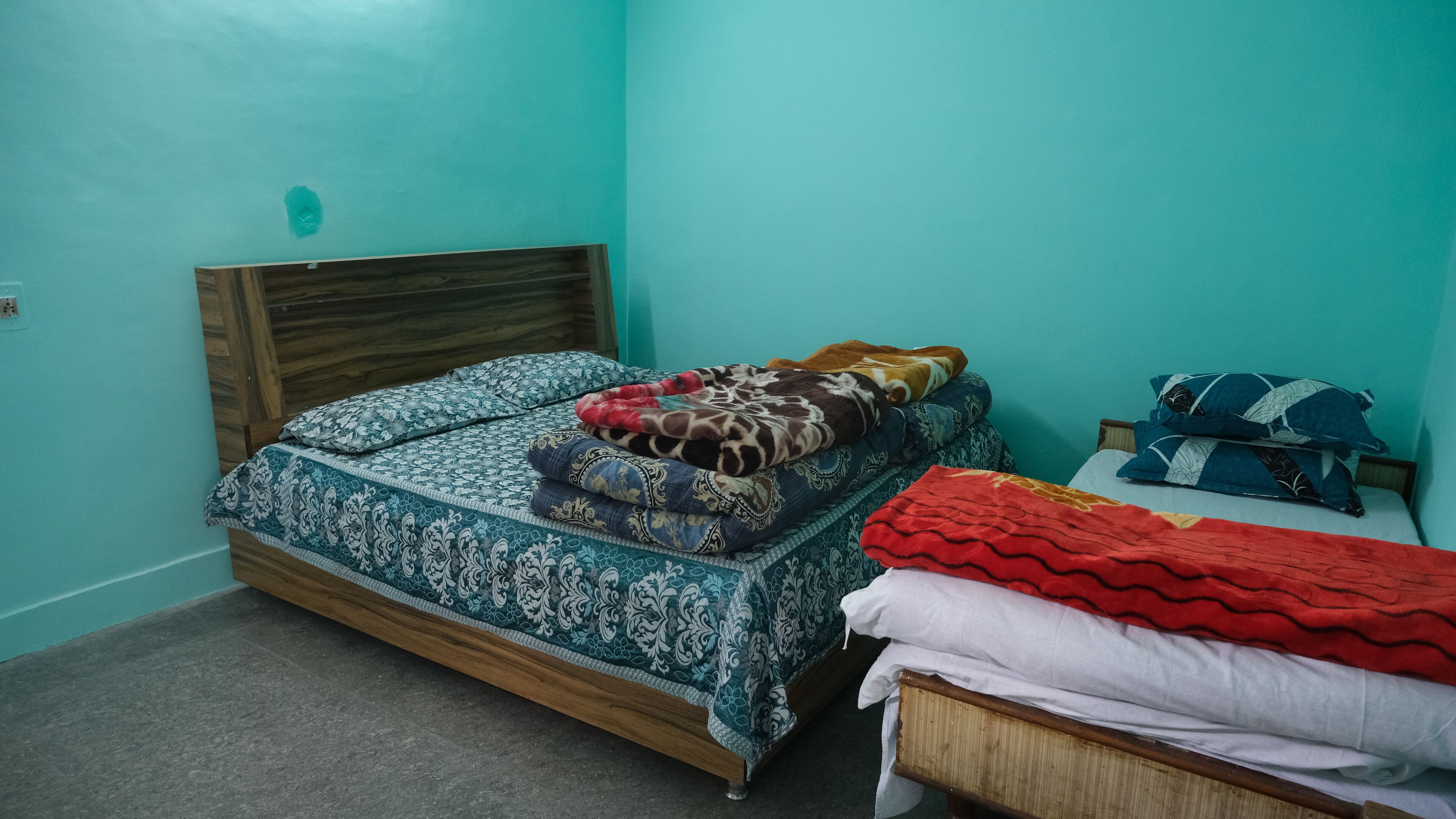 A room with a bed, a smaller bed, and a nightstand.