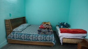 A room with a bed, a small table, and a wall with a wooden headboard.