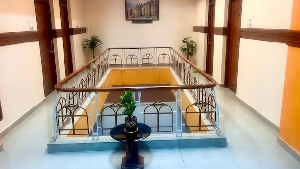 A hotel lobby with a central staircase, a small table with a plant, and a framed picture on the wall. - HOTEL TAJ MAHAL (Bengaluru)