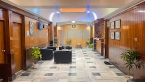 A hotel lobby with a check-in counter, seating area, and wooden paneling. - HOTEL TAJ MAHAL (Bengaluru)