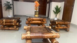 A room with a round glass table, bamboo furniture, and potted plants. - HOTEL TAJ MAHAL (Bengaluru)