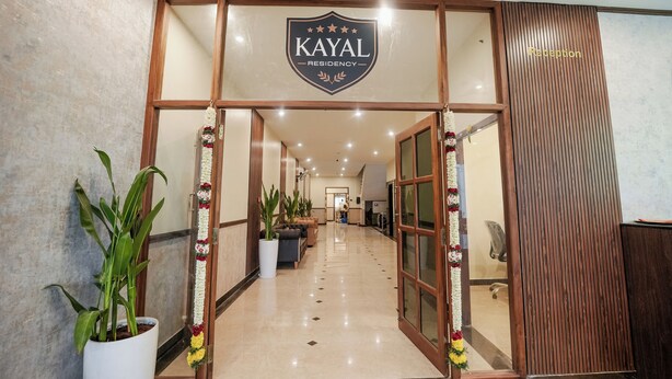 A reception area with a sign reading "KAYAL RESIDENCY," potted plants, and a reception desk. - KAYAL RESIDENCY (Gobichettipalayam)