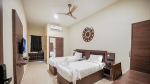 A hotel room with two beds, a TV, a ceiling fan, and a decorative wall piece. - KAYAL RESIDENCY (Gobichettipalayam)