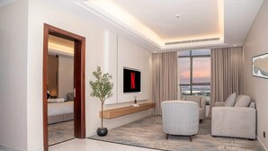 A modern living room with a sofa, a chair, a TV, and a plant.