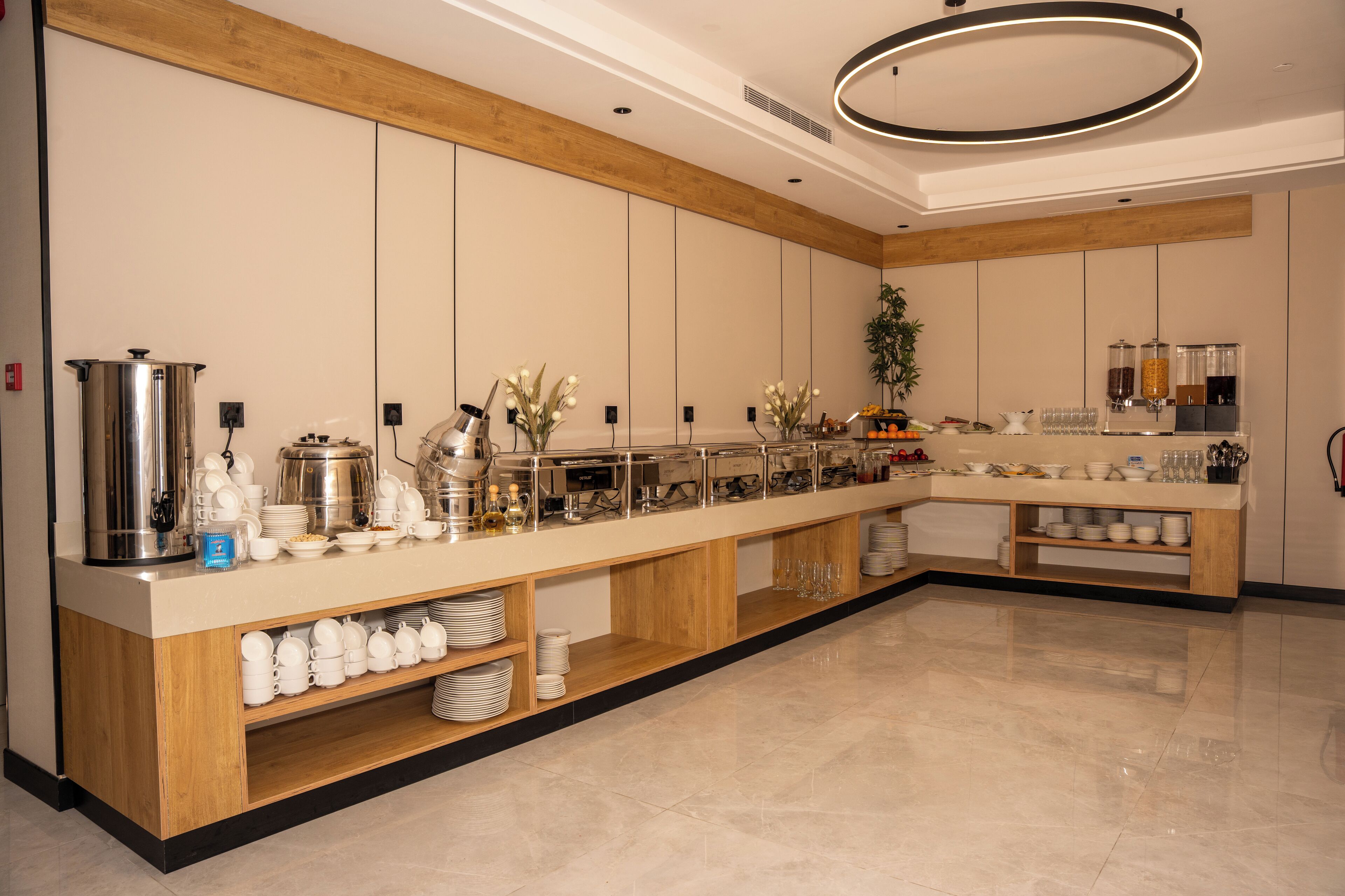 A modern kitchen with a long counter, stainless steel appliances, and a variety of dishes and utensils.