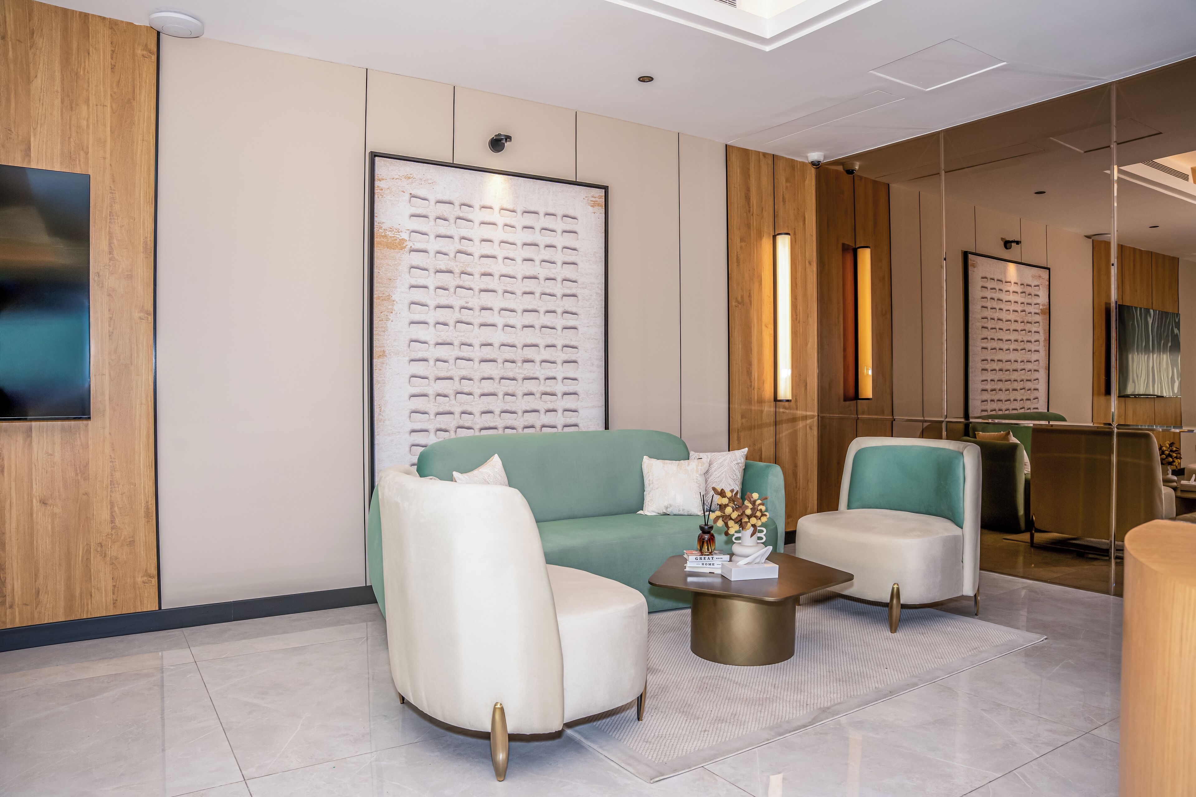 A modern lobby with a green sofa, white armchairs, and a coffee table.