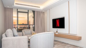 A modern living room with a sofa, ottoman, and a TV mounted on the wall.