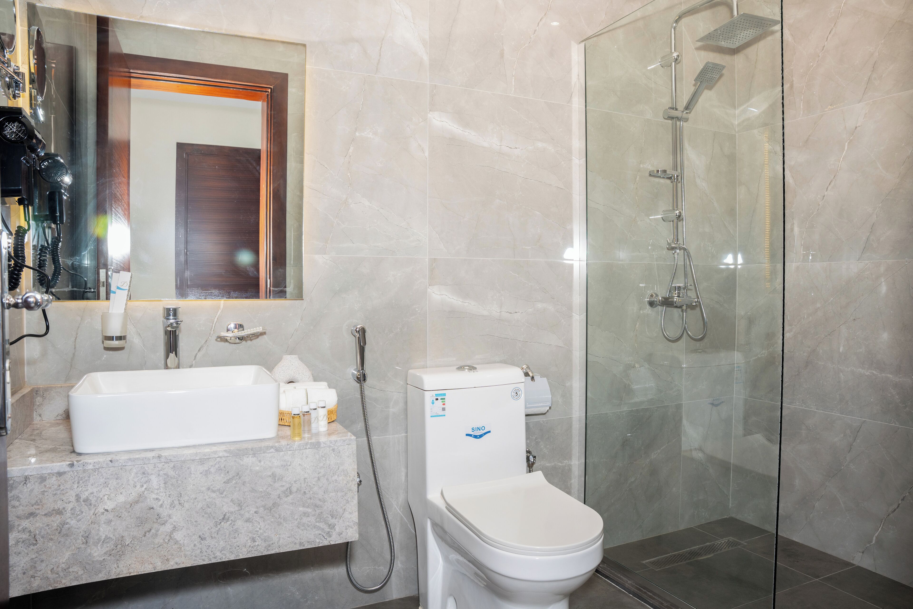 A modern bathroom with a white sink, mirror, and toilet.