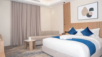 Une chambre d’hôtel avec un lit, un canapé, une petite table et une œuvre d’art accrochée au mur.