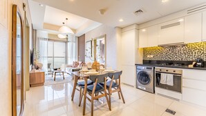 Une cuisine moderne avec des meubles blancs, un four encastré et un lave-linge.