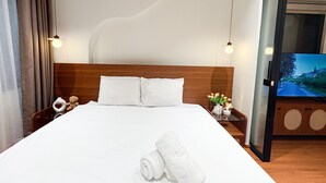 A neatly made bed with white linens, a teddy bear, and a rolled towel on the bed. - GAIA House Le Duan (Hanoi)