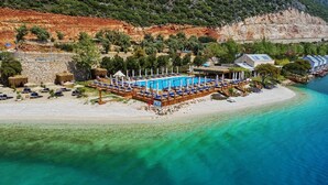 An aerial view of a beachside resort with a swimming pool, sun loungers, and a wooden deck. - Doria Hotel&Yacht Club (Kaş)