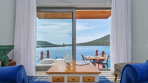 A room with a view of a body of water, a wooden table, and blue chairs. - Doria Hotel&Yacht Club (Kaş)