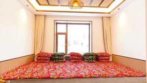 Quarto com cama, cortinas, janela e luminária no teto.