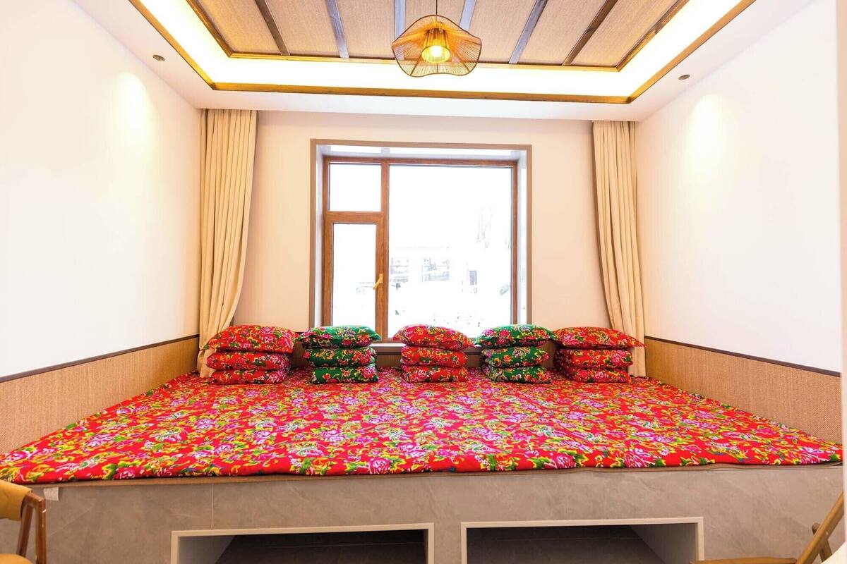 A bedroom with a bed, curtains, a window, and a ceiling light fixture.