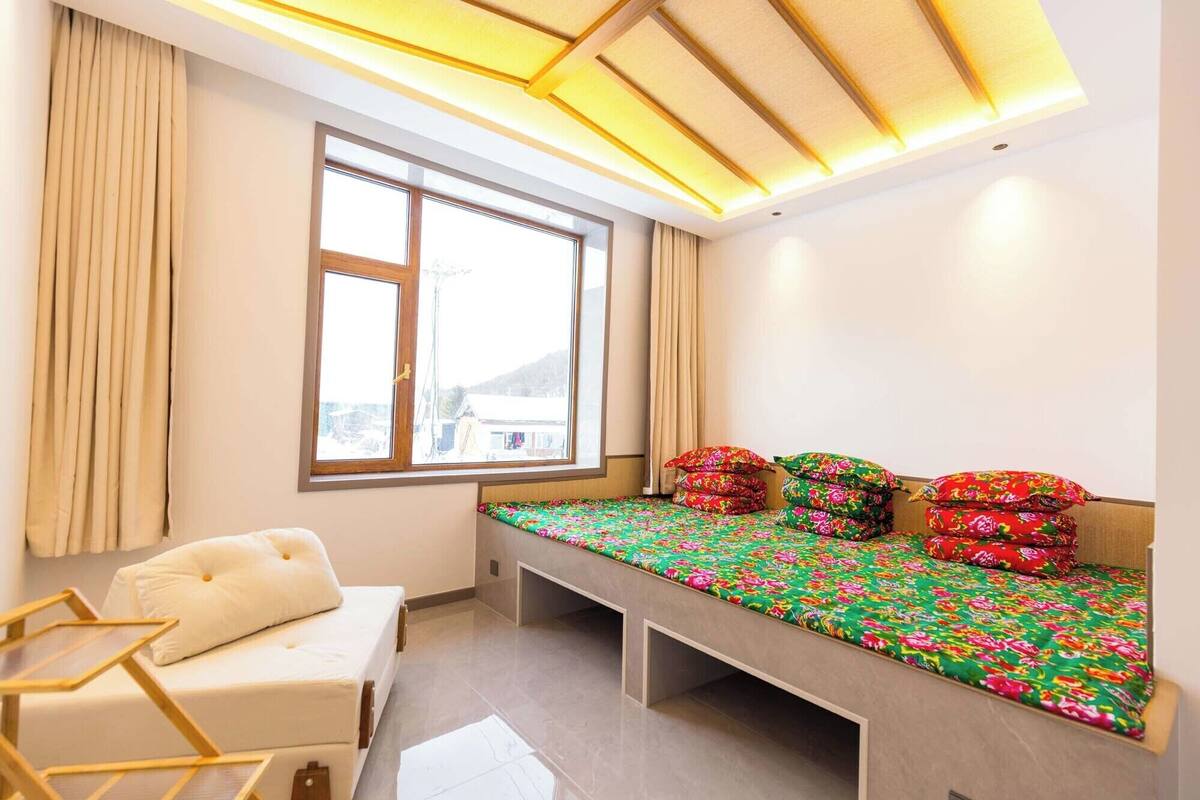 A bedroom with a bed, a chair, a window, and a ceiling light fixture.