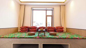 Quarto com assento à janela, com colcha florida e vários almofadas.