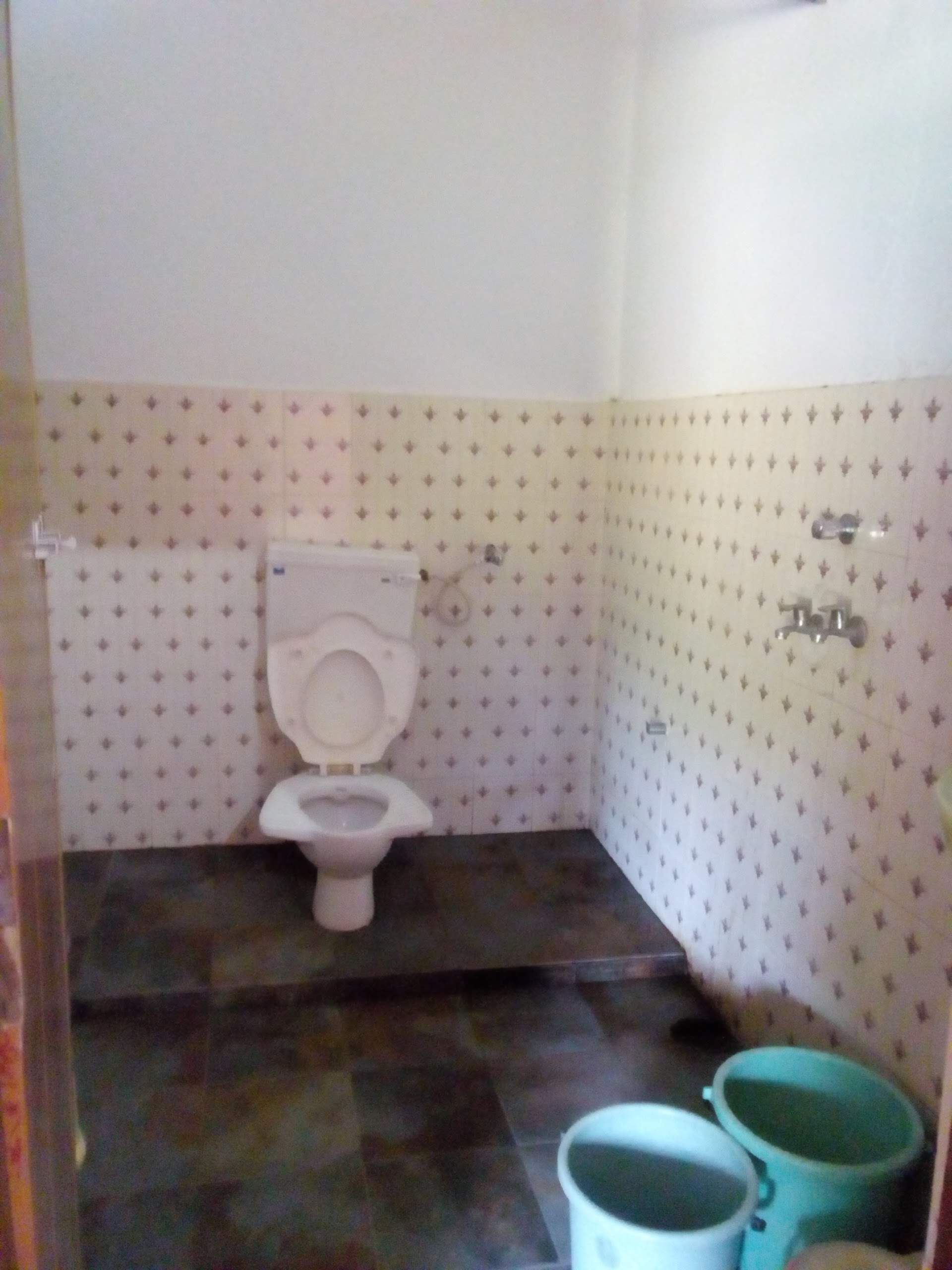 Une petite salle de bain avec des toilettes, un lavabo et deux seaux.