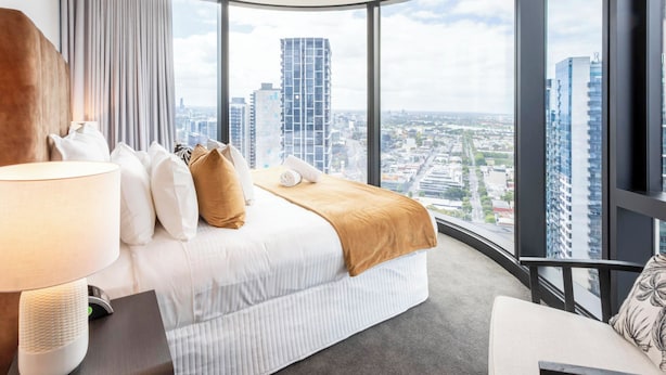 A hotel room with a large bed, a bedside table with a lamp, a chair, and a view of the cityscape through large windows. - The Queensbridge Skyline Suite, Heated Pool, Gym, Sauna, Steam next to Casino (Southbank)