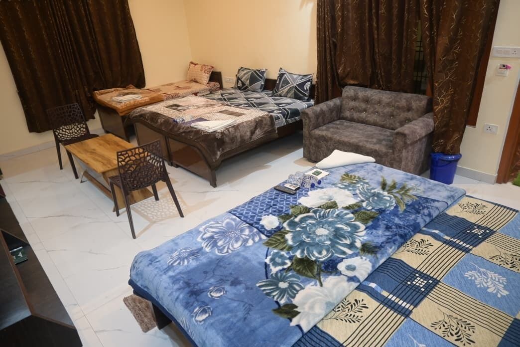 A bedroom with a bed, a sofa, a chair, and a small table.